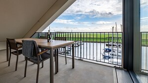 Ein Balkon mit Tisch und Stühlen mit Blick auf einen Hafen und Boote.