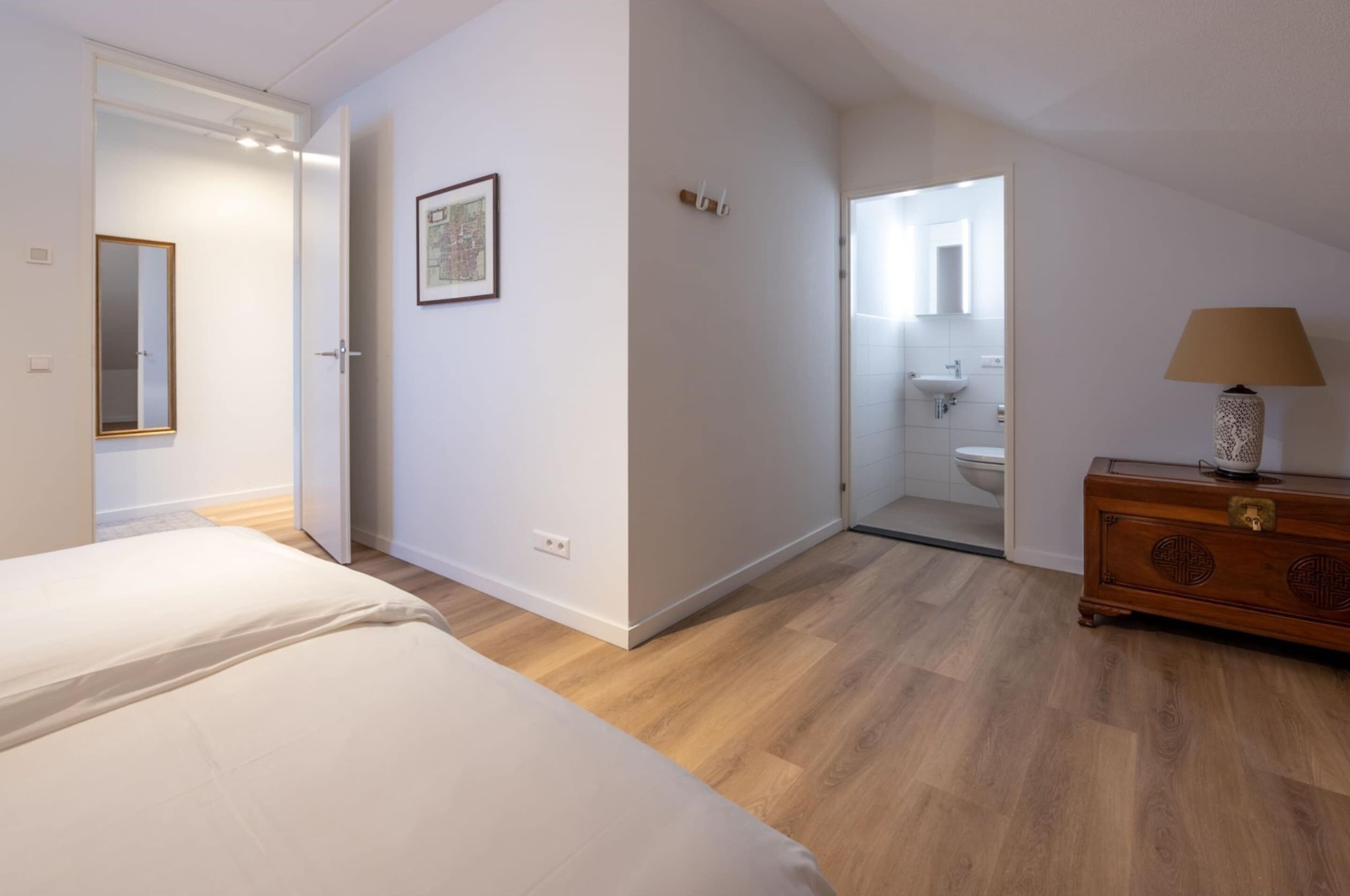 A bedroom with a bed, a dresser, and a bathroom visible through an open door.