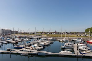 Ein Yachthafen mit mehreren angedockten Booten, einer hölzernen Pier und Gebäuden im Hintergrund.
