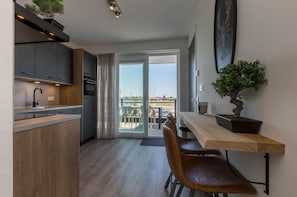 A modern kitchen with a dining area, a sliding glass door to an outdoor terrace, and a potted plant on the table. - Apartment Sint Annaland With Marina Views (Sint-Annaland)