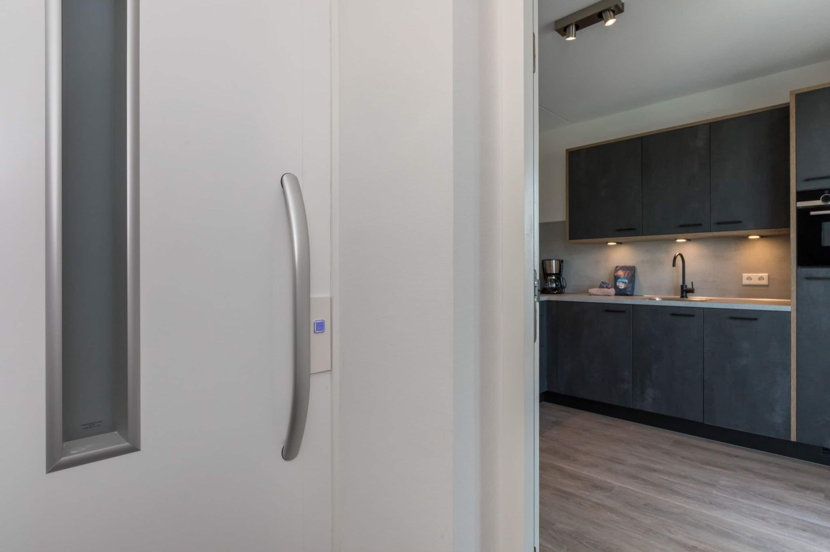 A modern kitchen with dark cabinets, a stainless steel refrigerator, and a built-in oven.