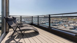 Un balcon donnant sur une marina, équipé de chaises longues et d’une rambarde.