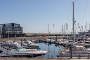 Un port esportiu amb barques amarrades, un edifici modern i un cel serè.