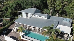 Ett modernt hus med en stor swimmingpool, en täckt uteplats och ett carport.