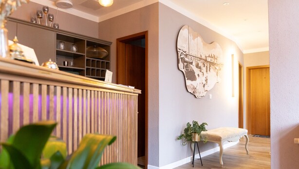 A modern kitchen with wooden cabinets, a built-in shelf, and a countertop with various items. - Hotel Balticpetite (Heringsdorf)