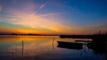 A calm lake at sunset with a boat docked on the right.