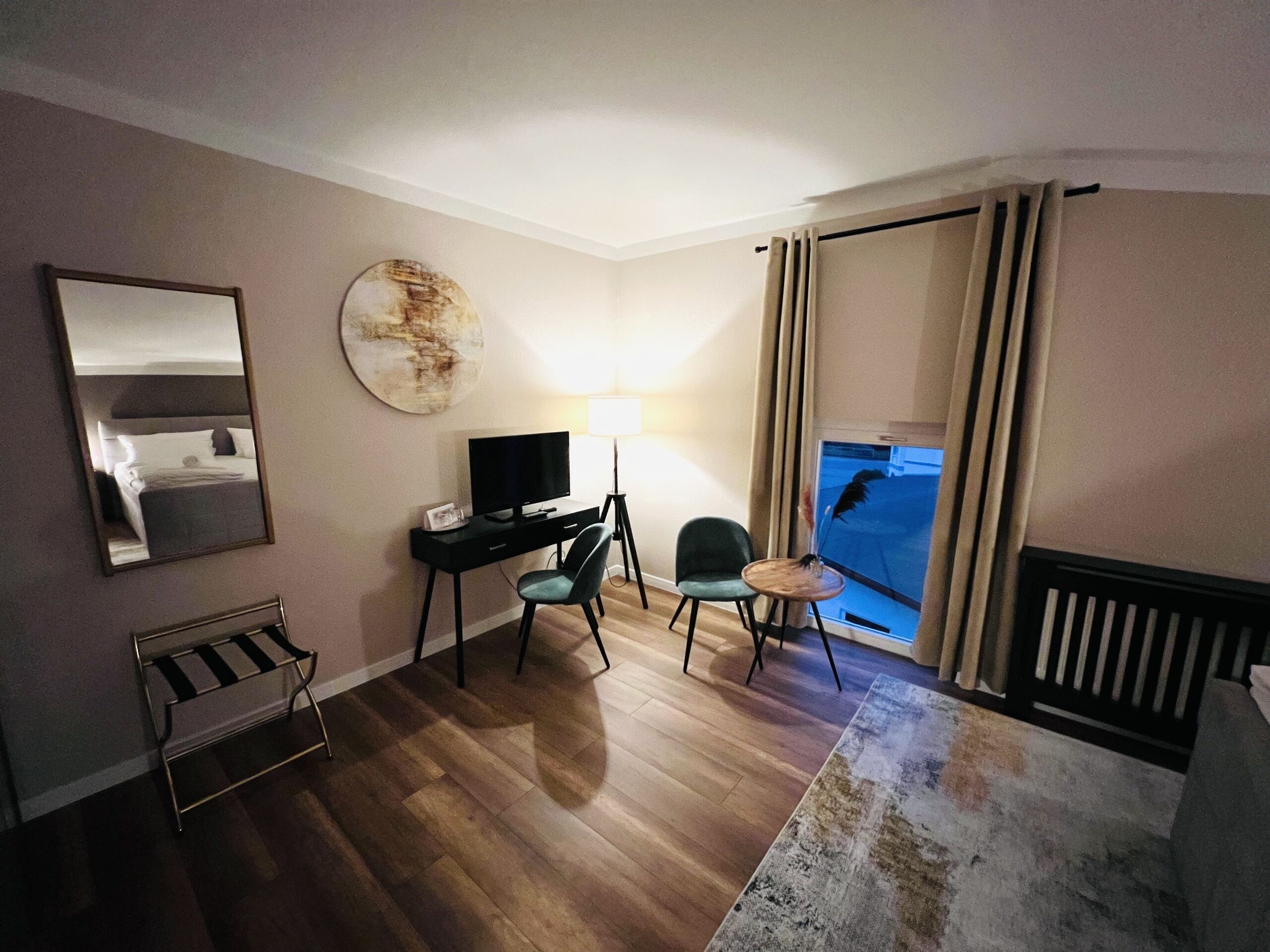 Une chambre d’hôtel avec un lit, un bureau avec une télévision, une chaise, une lampe et une vue sur l’extérieur.