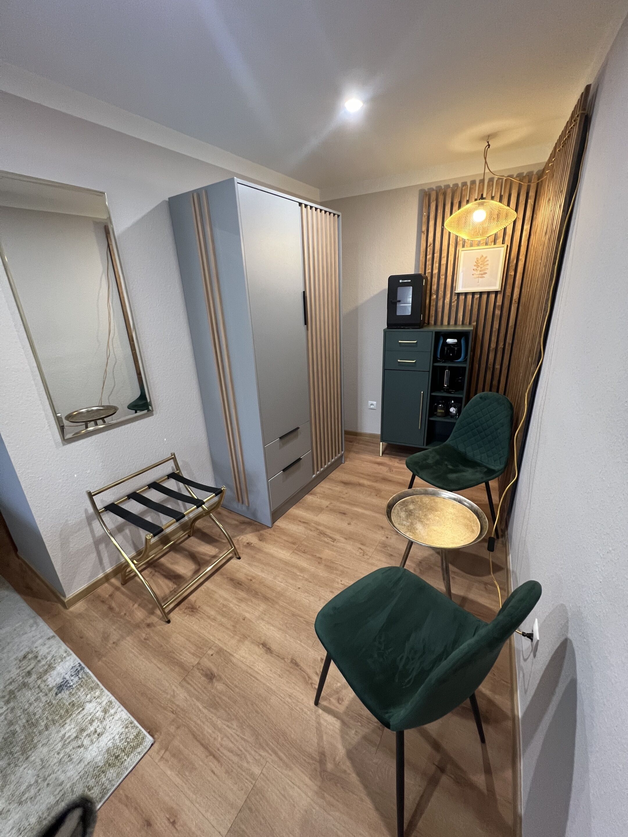 Un espacio habitable compacto con zona de estar, una mesita, un mueble con electrodomésticos y un espejo.
