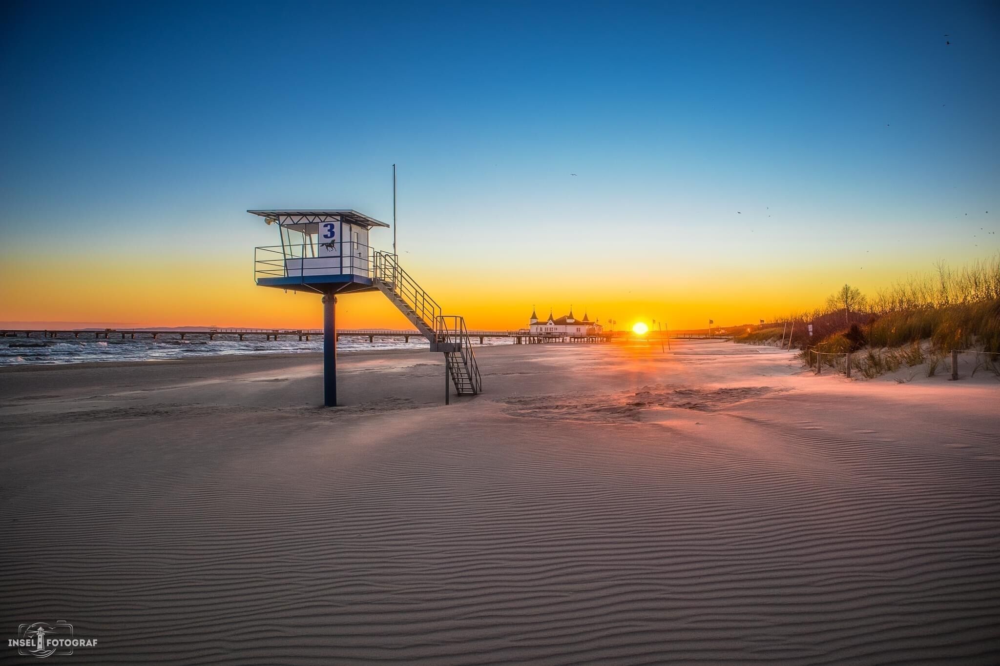 A lifeguard tower on a beach at sunset.