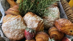 A variety of pastries including croissants and scones, some with strawberries, arranged on a tray. - West Palm Hotel (Chaguaramas)