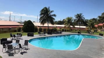 Una piscina al aire libre, sombrillas, sillones reclinables de piscina