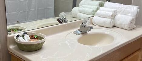 Un baño con un lavabo color crema, armarios de madera, un espejo y un perchero con toallas dobladas.