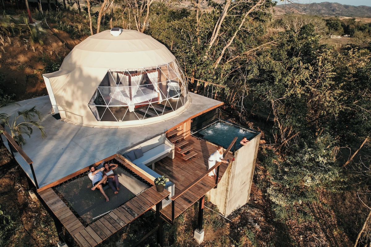 Uma tenda em formato de cúpula com deck de madeira e piscina.
