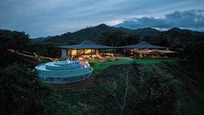 Un resort moderno con piscina, mobiliario exterior y un amplio patio cubierto.