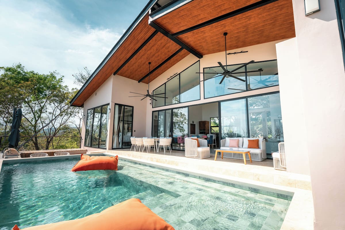 A modern house with a swimming pool, large windows, and outdoor furniture.