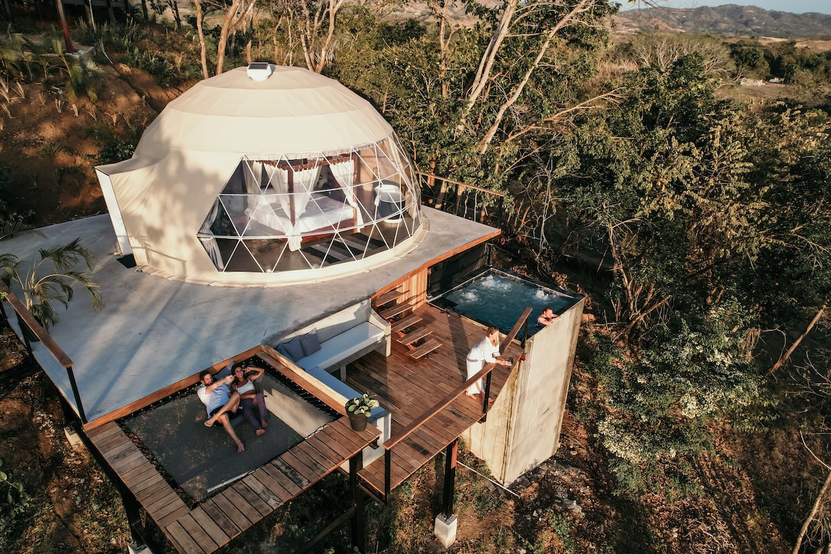 A dome-shaped tent with a wooden deck and a pool.