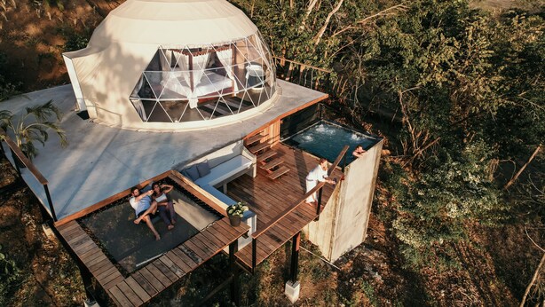 Una tienda de campaña con forma de cúpula, un deck de madera y una piscina.