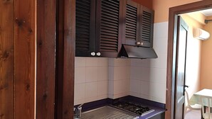 A compact kitchen with a gas stove, a sink, and dark wooden cabinets. - Beautiful Apartment in Vecchia With Pool (Briatico)