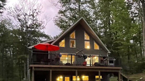 A two-story log cabin with a balcony and a covered porch.