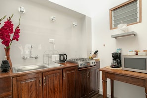A modern kitchen with a stainless steel sink, wooden cabinets, a gas stove, and a microwave.