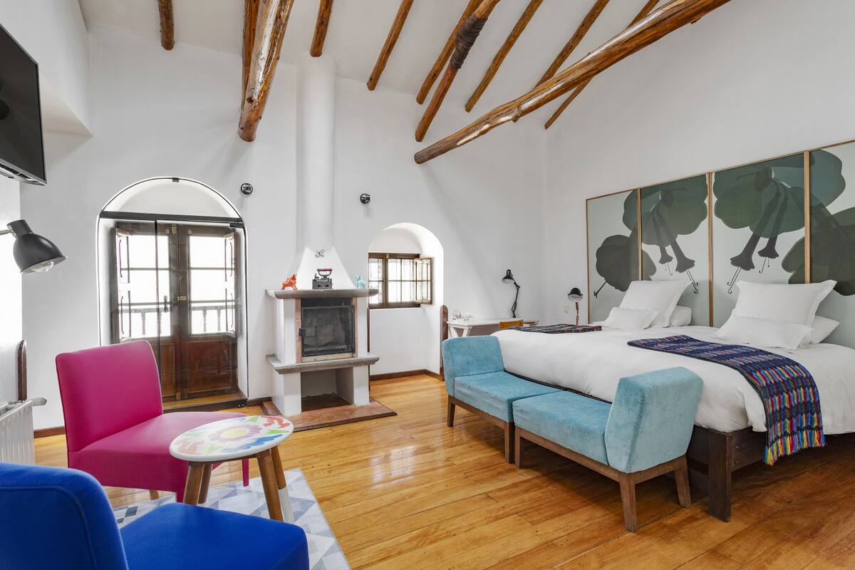 Un dormitorio con cama, televisor, chimenea y un ventanal grande.