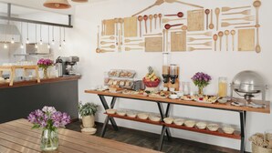 A modern kitchen with wooden utensils on the wall, a buffet table with food, and a coffee station. - Andenes (Cusco)
