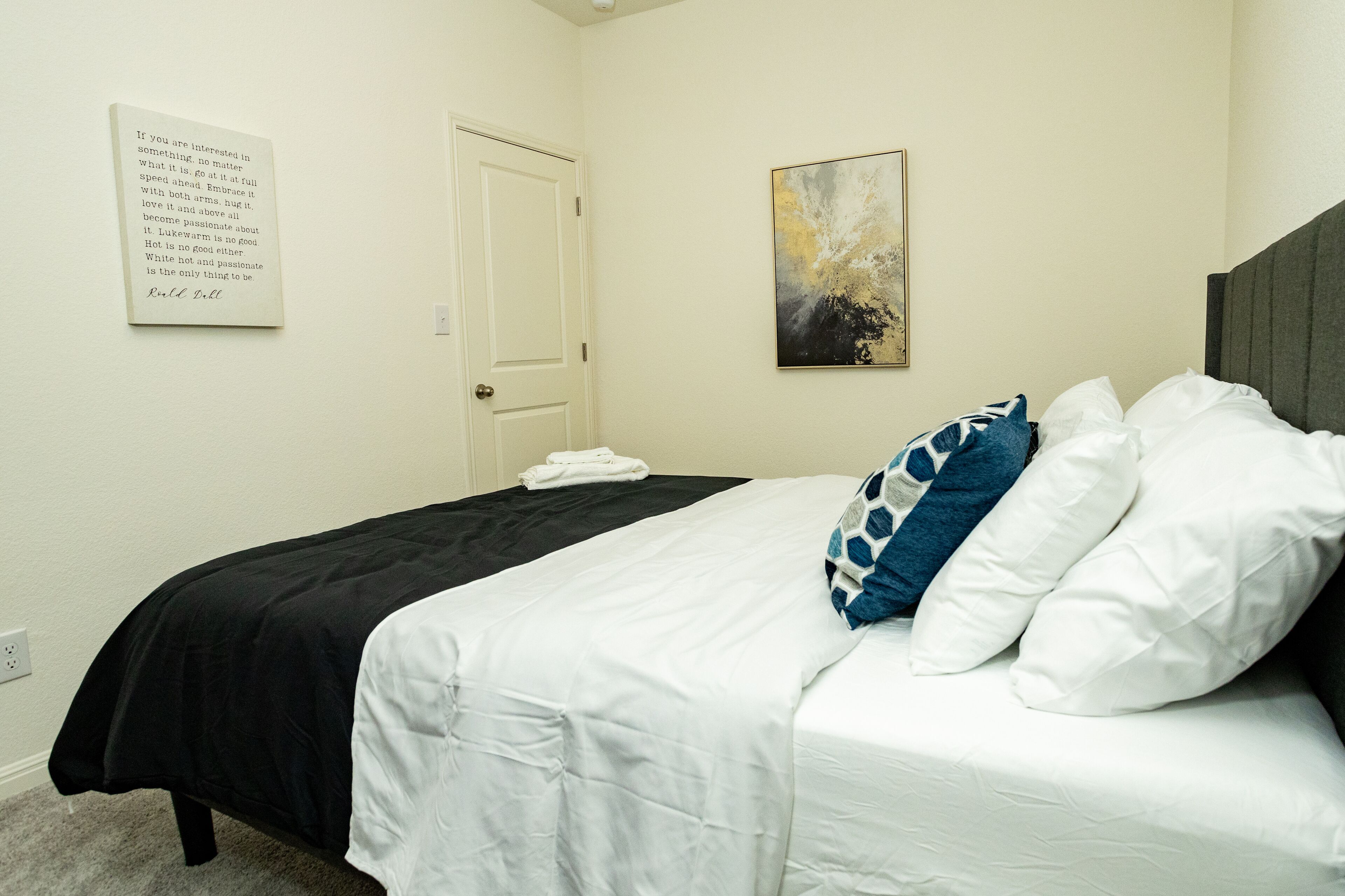 Une chambre d’hôtel avec un lit, une porte et une œuvre d’art accrochée au mur.