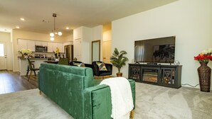 A living room with a green sofa, a flat-screen TV, and a fireplace.