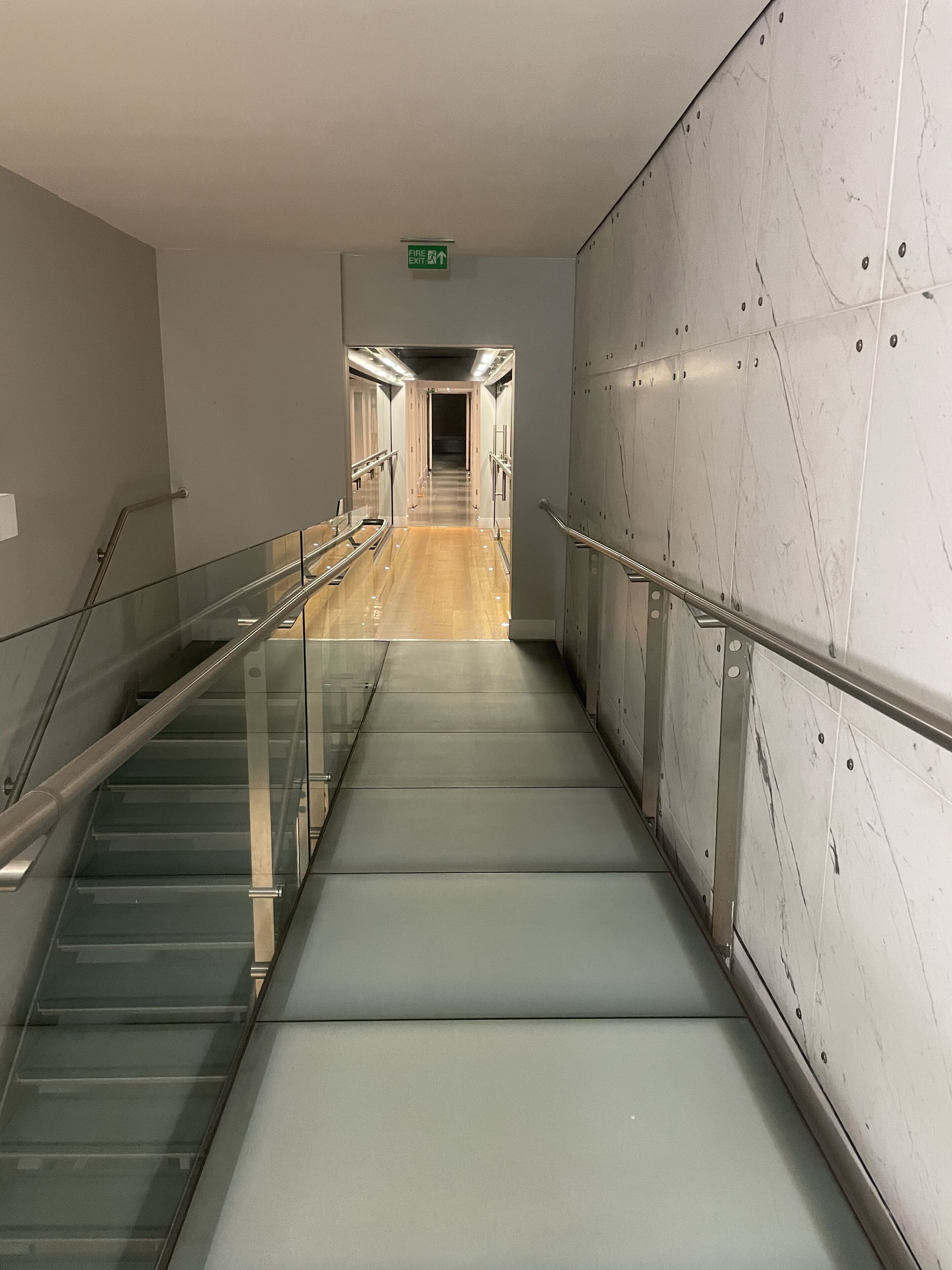 A modern elevator shaft with glass railings and a marble wall.