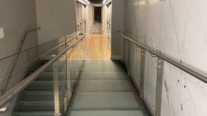 Une cage d’ascenseur moderne avec des garde-corps en verre et un mur en marbre.