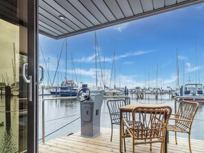 A deck with a table and chairs overlooking a marina with multiple sailboats. - Luxury Houseboat in Volendam Marina (Volendam)