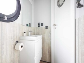A modern bathroom with a white sink, a mirror, and a toilet paper holder. - Luxury Houseboat in Volendam Marina (Volendam)