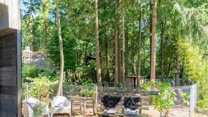 A wooden bench with a metal fence in a wooded area with trees and a thatched-roof structure. - Holiday Home in Gelderland Near Den Bramel (Lochem)