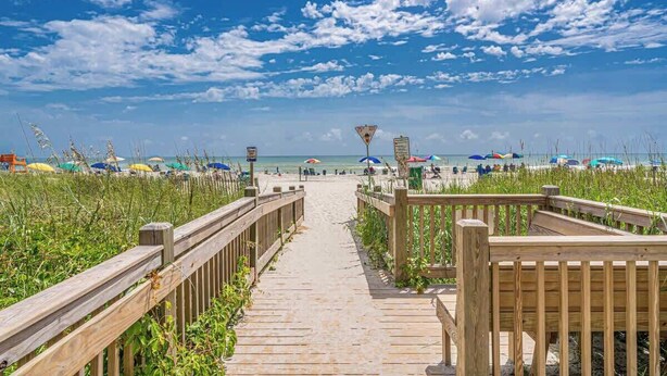 A wooden boardwalk leading to a beach with umbrellas and beach chairs. - 1BR - Sleeps 6 - Steps to The Beach - Pool - 7500 (Myrtle Beach)