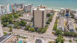 A coastal urban area with high-rise buildings, a road, and a beach in the background. - 1BR - Sleeps 6 - Steps to The Beach - Pool - 7500 (Myrtle Beach)