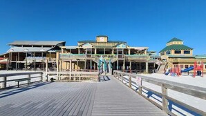 A multi-story building with a wooden deck in front, a playground on the right, and a clear blue sky. - POSH LIVING in Fort Walton Beach (Fort Walton Beach)