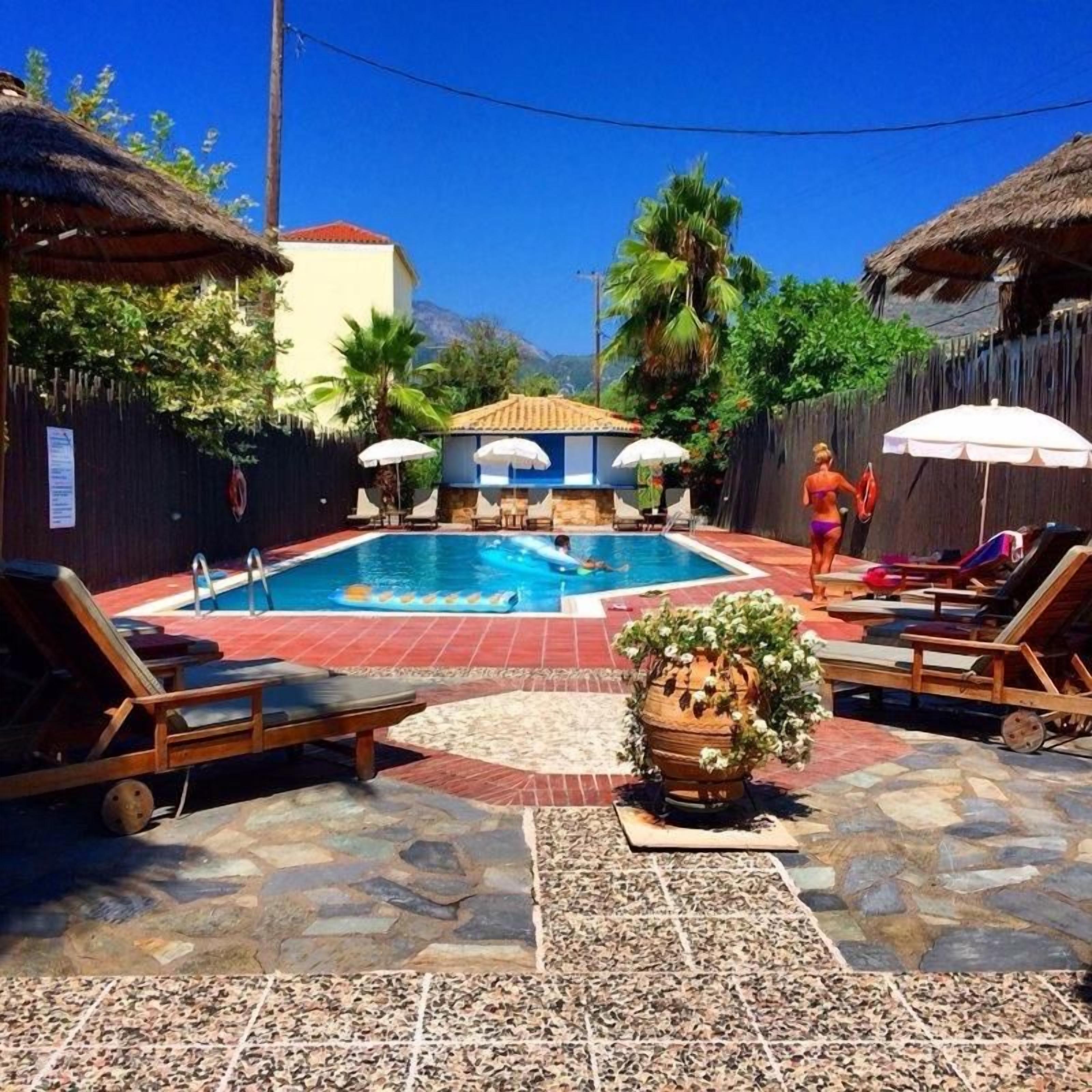 A swimming pool area with lounge chairs, umbrellas, and a decorative planter.