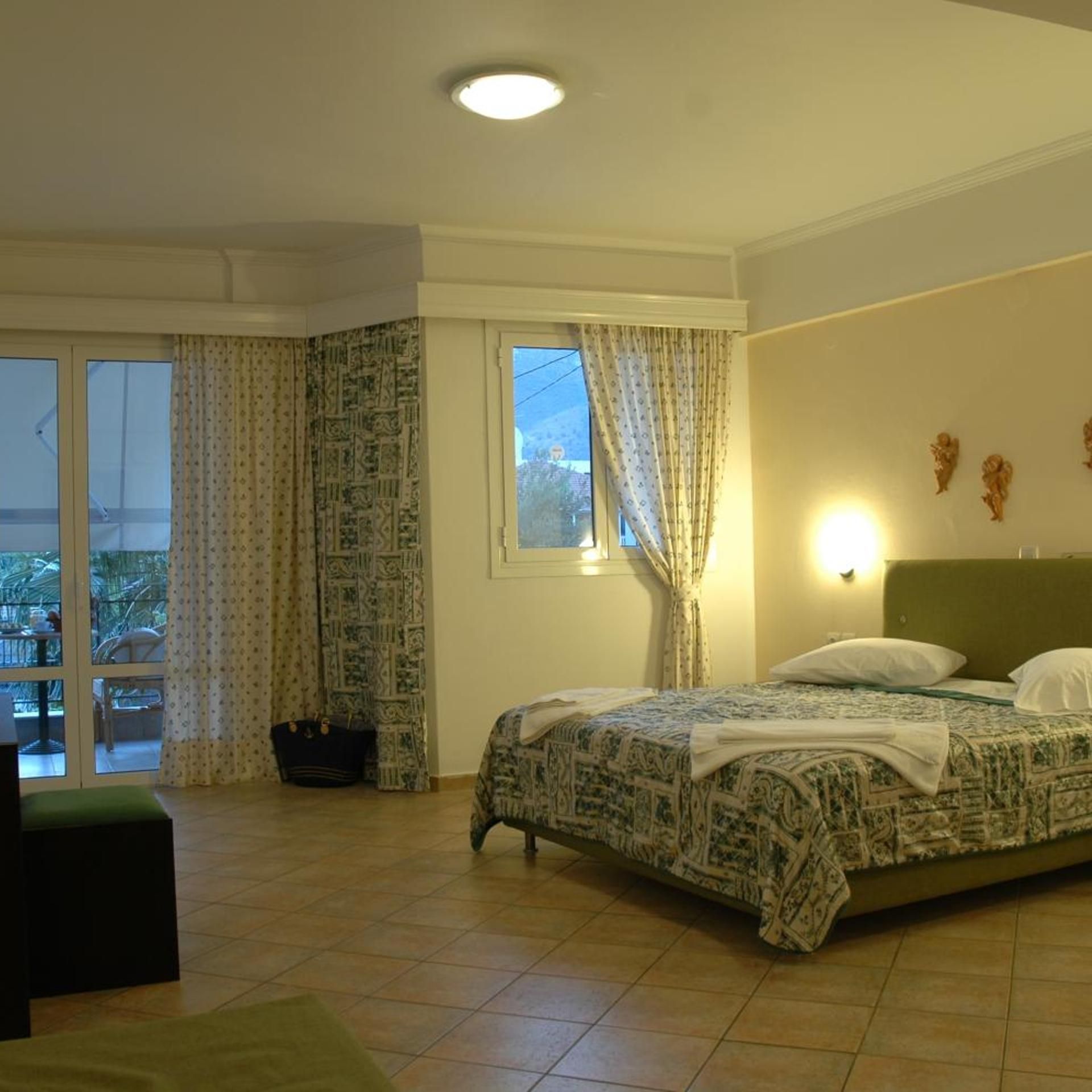 Quarto de hotel com cama, janela com cortinas, varanda e vista para o exterior.