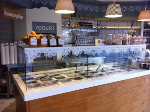 A yogurt station with various flavors and a coffee bar in the background. - Santa Maura (Lefkada)