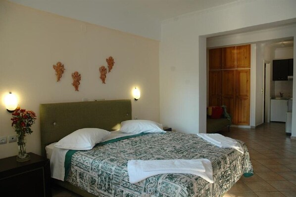 Habitación de hotel con cama, mesita de noche con un florero y un armario de madera.