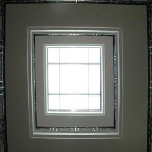 A square window with a grid pattern, surrounded by a decorative metal frame. - Santa Maura (Lefkada)