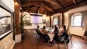 A conference room with a wooden ceiling, a projector screen, and a table with people seated around it.