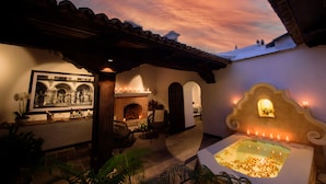 Un patio acogedor con chimenea, zona de estar y una pared decorativa con luces.