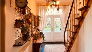 A hallway with a wooden staircase, a hanging light fixture, and a wall-mounted clock. - Geulzicht Hotel (Schin op Geul)