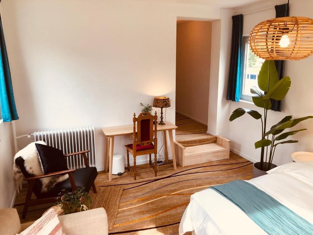 Une chambre à coucher comprenant un lit, un bureau, une chaise, un radiateur, un escalier et une plante.