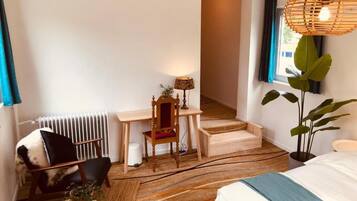 Une chambre à coucher comprenant un lit, un bureau, une chaise, un radiateur, un escalier et une plante.