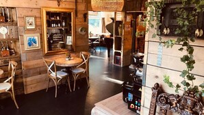 A rustic interior with wooden walls, a round table with chairs, and a bar area with shelves of bottles. - Geulzicht Hotel (Schin op Geul)
