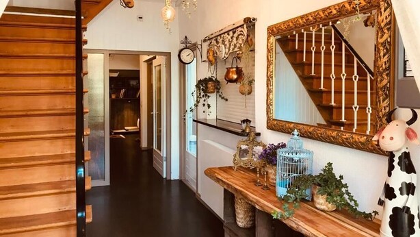 A staircase with wooden steps and a metal railing, leading to a landing with a wooden console table. - Geulzicht Hotel (Schin op Geul)