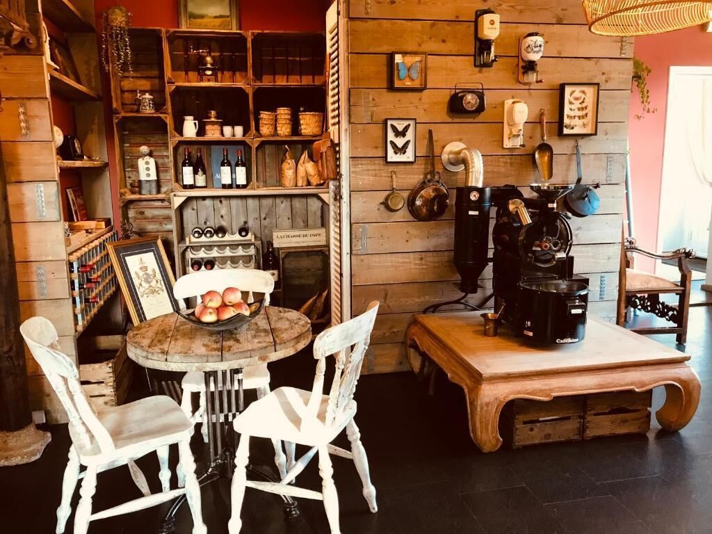 Une cuisine rustique avec des étagères en bois, une machine à café et une table entourée de chaises.