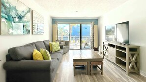 Una sala de estar con un sofá gris, una mesa de centro de madera y un mueble para televisor.